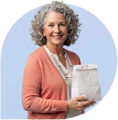 A smiling woman with curly silver hair holding a white paper bag.