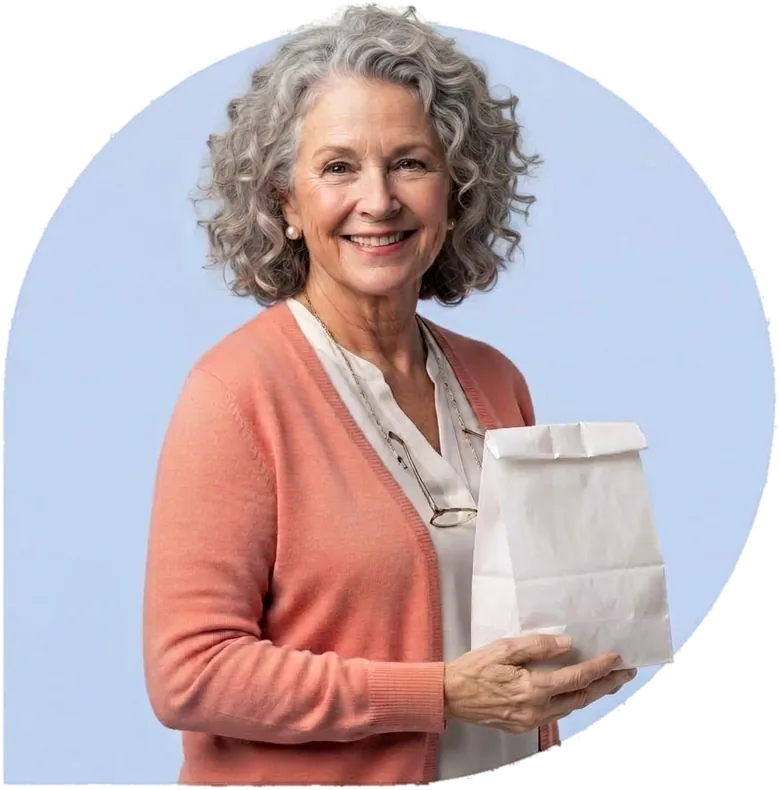 A smiling woman with curly silver hair holding a white paper bag.