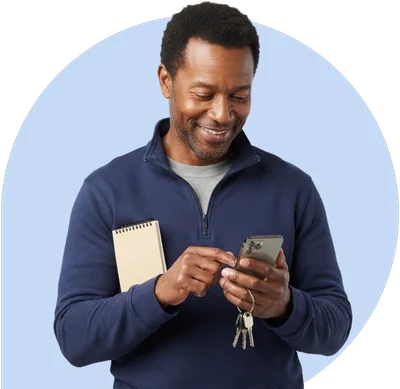 A man with a small notebook and his car keys, checking a drive on his phone.